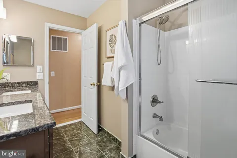a bathroom with a granite countertop tub shower and sink