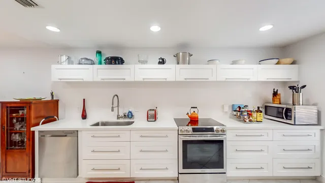 a kitchen with white cabinets and appliances