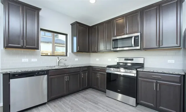 a kitchen with cabinets stainless steel appliances a sink and wooden floor