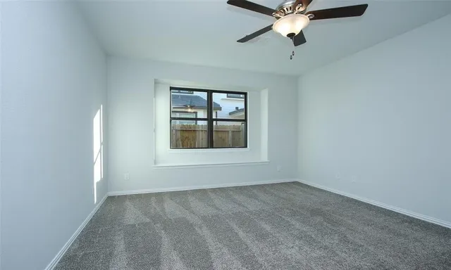 an empty room with chandelier fan and windows