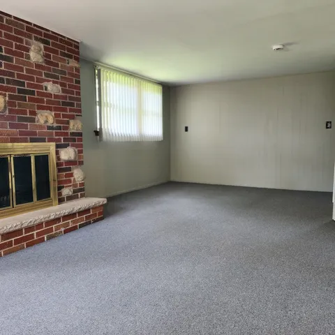 a view of an empty room with a fireplace and windows