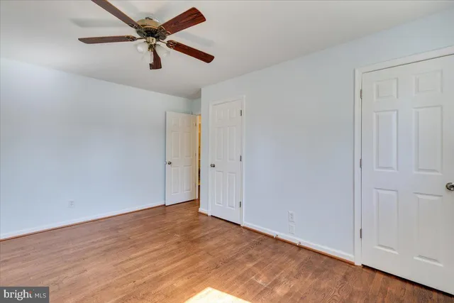 an empty room with wooden floor ceiling fan and window