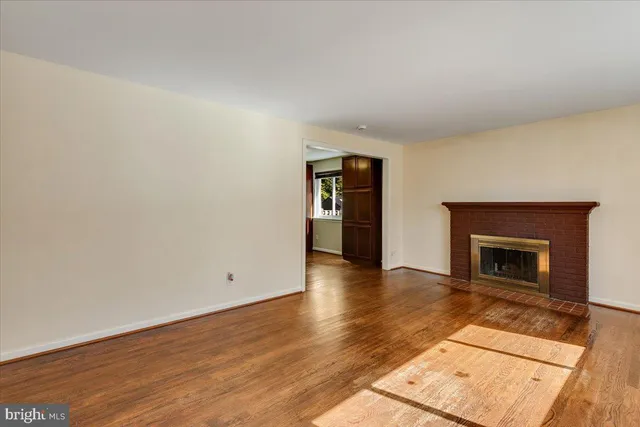 an empty room with wooden floor and fireplace