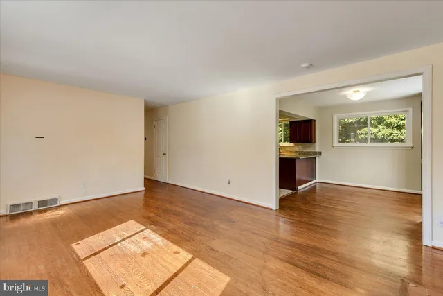 an empty room with wooden floor fireplace and windows