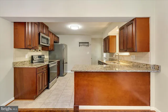 a kitchen with kitchen island granite countertop wooden cabinets a stove top oven a sink and dishwasher