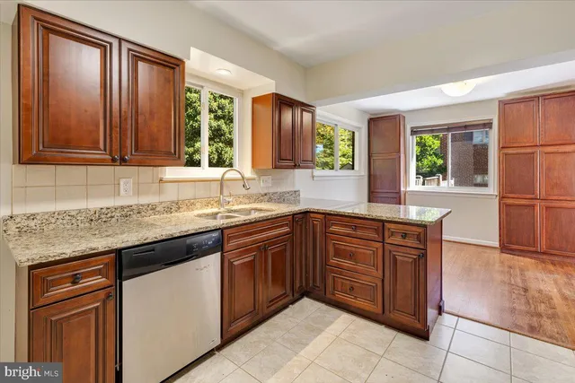 a kitchen with stainless steel appliances granite countertop wooden cabinets a sink and dishwasher with a large window