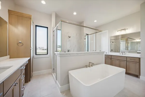 a bathroom with a bathtub a sink a mirror a vanity and a shower