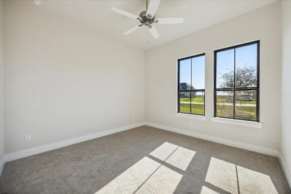 an empty room with windows and fan