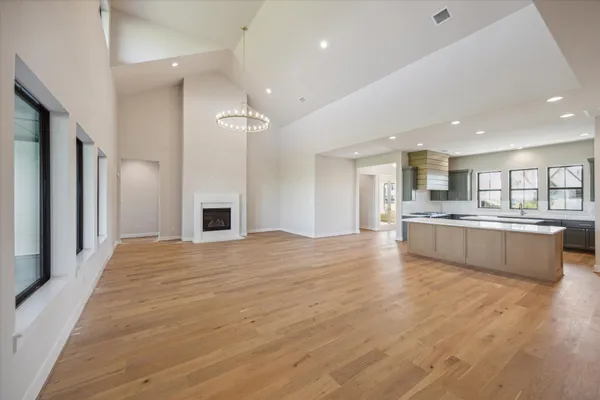 a large kitchen with a center island wooden floor stainless steel appliances and windows