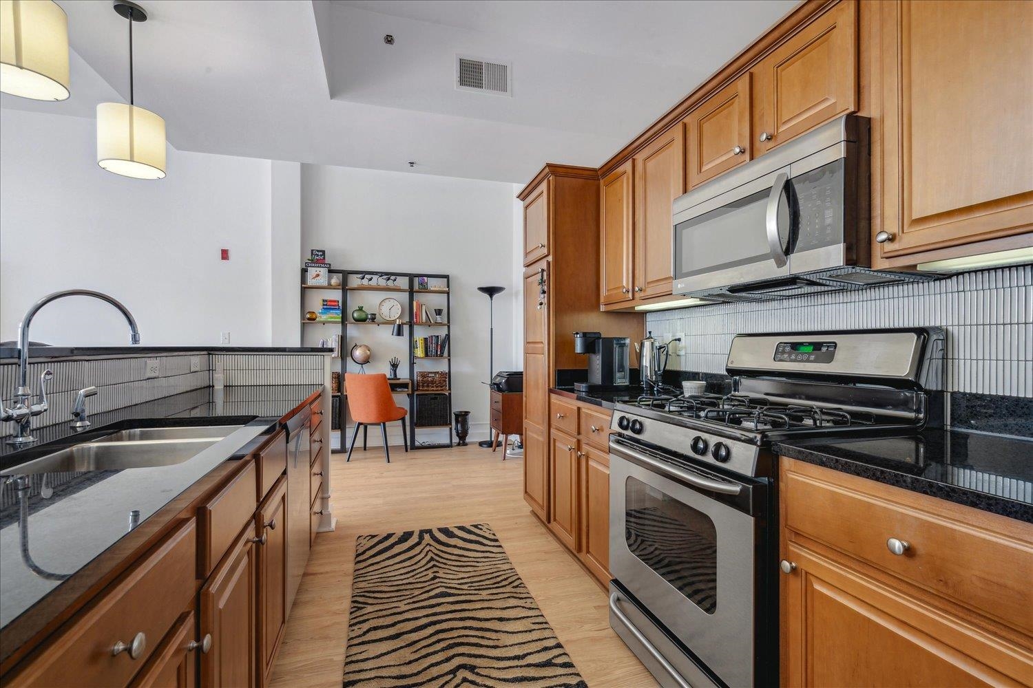 648 Riverside Drive, Unit 411 Memphis, TN 38103 - Photo 12 of 32 Kitchen with sink, hanging light fixtures, tasteful backsplash, light hardwood / wood-style floors, and appliances with stainless steel finishes