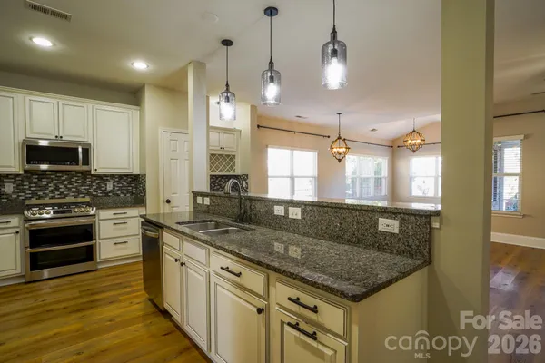 a kitchen with kitchen island granite countertop a sink a counter top space appliances and cabinets