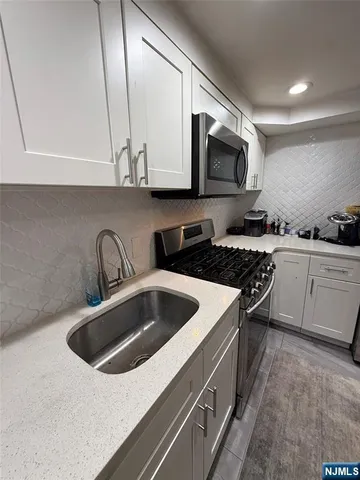a kitchen with stainless steel appliances granite countertop a sink a stove and a microwave oven with cabinets