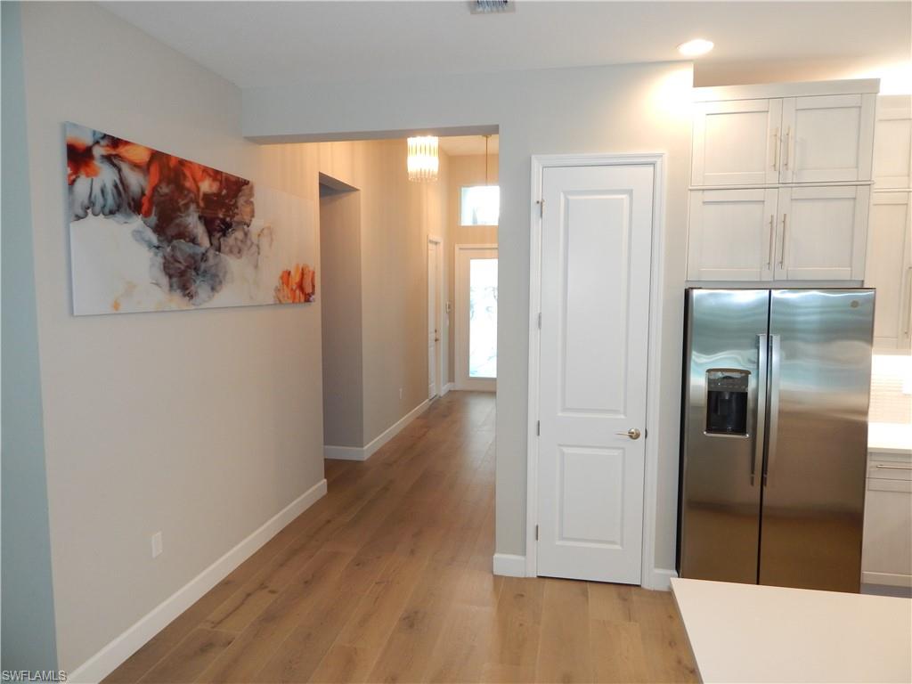 11331 Jacaranda Drive Naples, FL 34120 - Photo 20 of 47 Kitchen with stainless steel refrigerator with ice dispenser, light wood-style flooring, baseboards, white cabinets, and recessed lighting