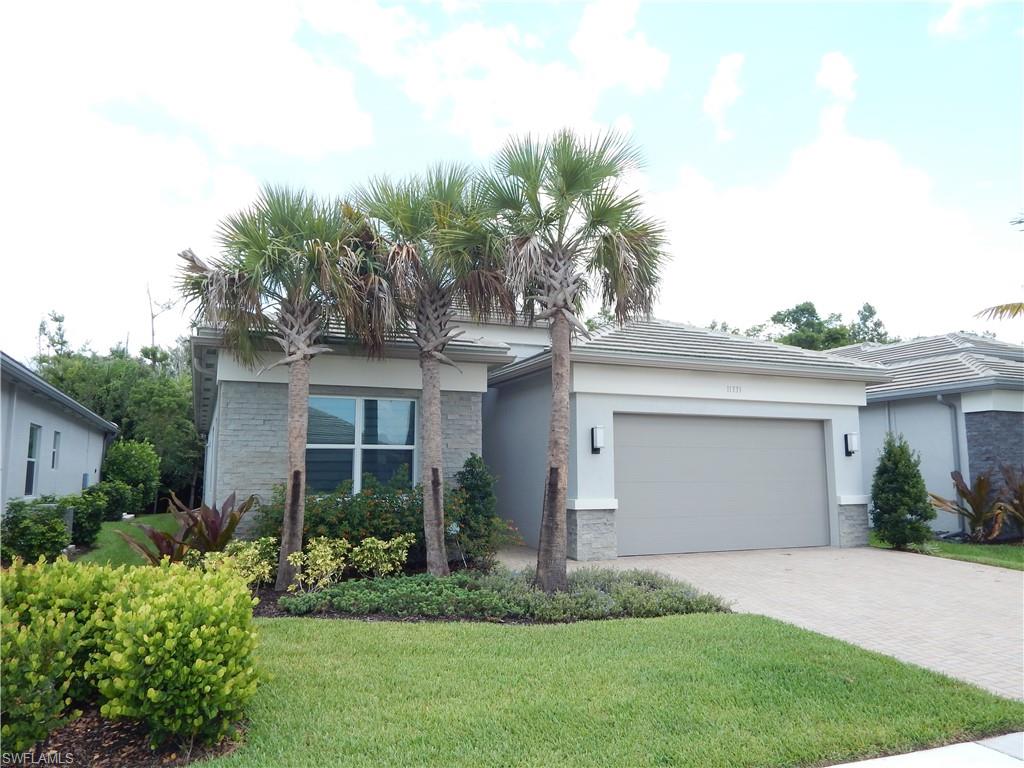 11331 Jacaranda Drive Naples, FL 34120 - Photo 2 of 47 View of front facade with stone siding, a garage, stucco siding, decorative driveway, and a front lawn