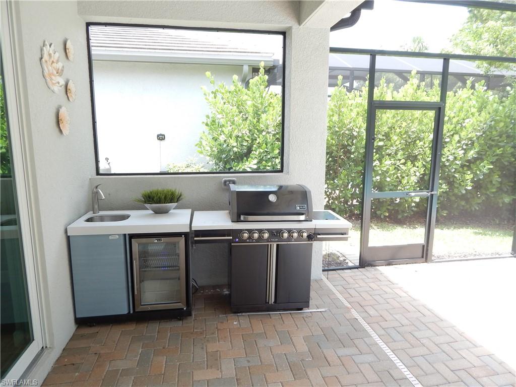 11331 Jacaranda Drive Naples, FL 34120 - Photo 28 of 47 View of patio / terrace featuring a grill, a sink, glass enclosure, and beverage cooler