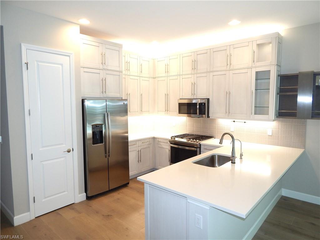 11331 Jacaranda Drive Naples, FL 34120 - Photo 9 of 47 Kitchen with stainless steel appliances, a peninsula, a sink, light wood-style floors, and recessed lighting