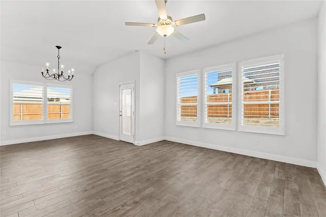 an empty room with chandelier fan and windows