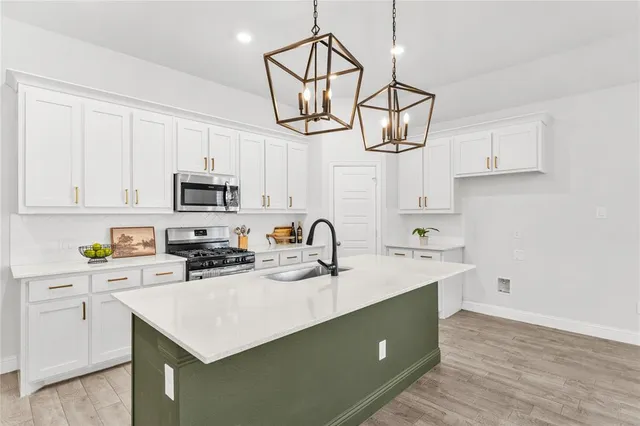 a kitchen with stainless steel appliances a sink a stove cabinets and wooden floor