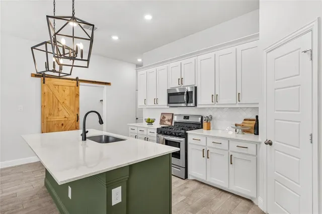a kitchen with white cabinets a sink dishwasher and a stove with wooden floor