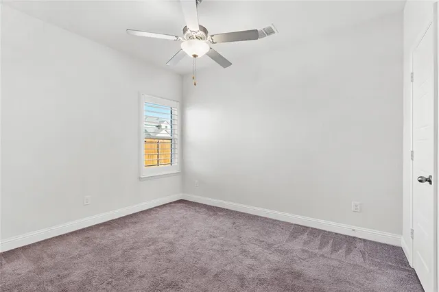 an empty room with a window and a ceiling fan