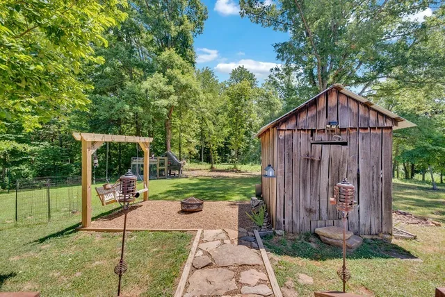 a view of a tiny house with a small yard and a large tree