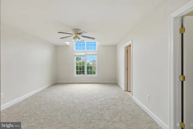 an empty room with a window and a fan