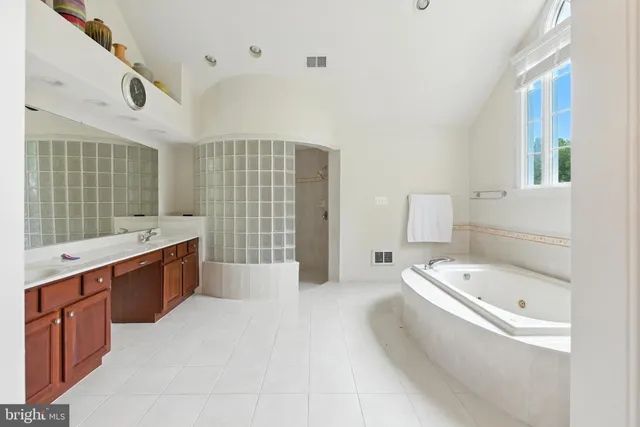 a spacious bathroom with a tub sink and mirror
