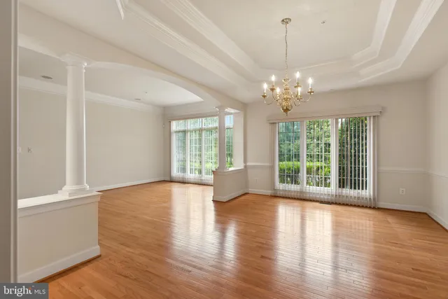 a view of an empty room with a window and kitchen view