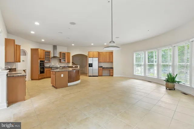 a large kitchen with stainless steel appliances granite countertop a large counter top a stove a sink dishwasher a refrigerator and cabinets with wooden floor