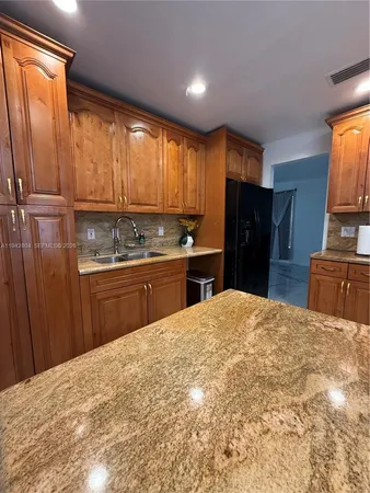 a kitchen with stainless steel appliances kitchen island granite countertop a stove top oven a sink a dining table and chairs with wooden floor