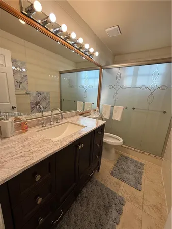a bathroom with a granite countertop toilet sink and mirror