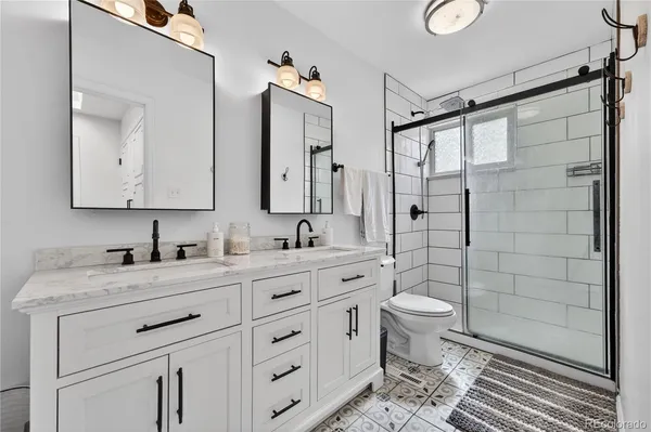a bathroom with a double vanity sink toilet and shower