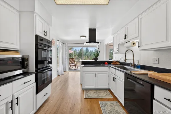 a kitchen with granite countertop a sink stainless steel appliances and white cabinets