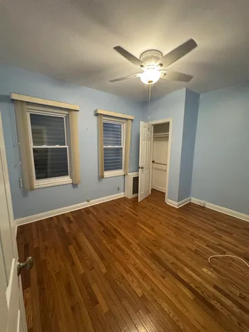 a view of empty room with wooden floor and fan