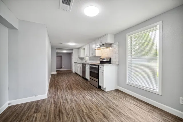 a kitchen with granite countertop a stove and a wooden floors