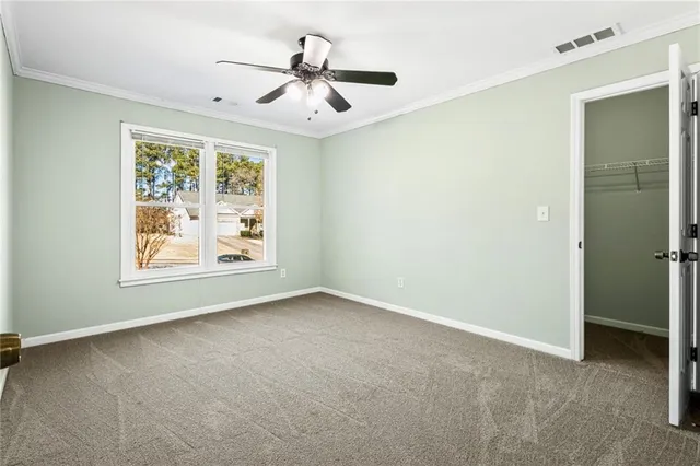 an empty room with windows and ceiling fan