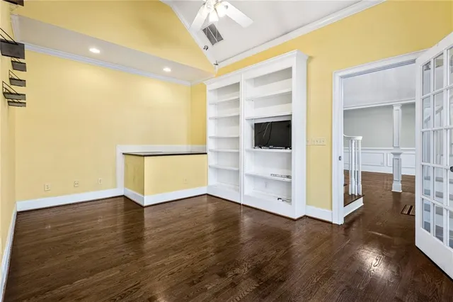a view of an empty room with wooden floor and a kitchen