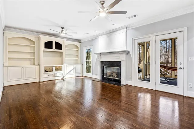 an empty room with wooden floor fireplace and windows