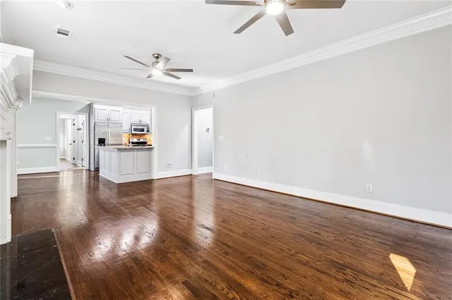a view of a livingroom with wooden floor a ceiling fan and staircase