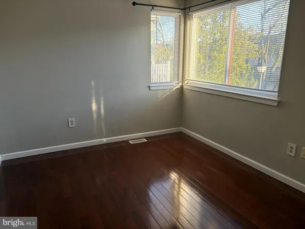 an empty room with wooden floor a chandelier and windows