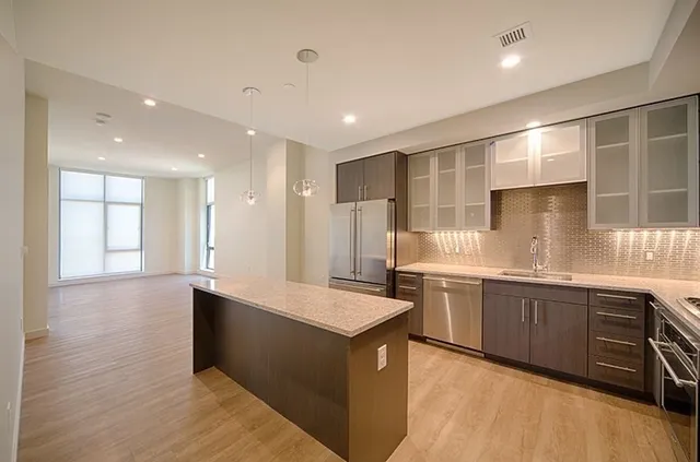 a large kitchen with stainless steel appliances granite countertop a large counter top a sink and a refrigerator