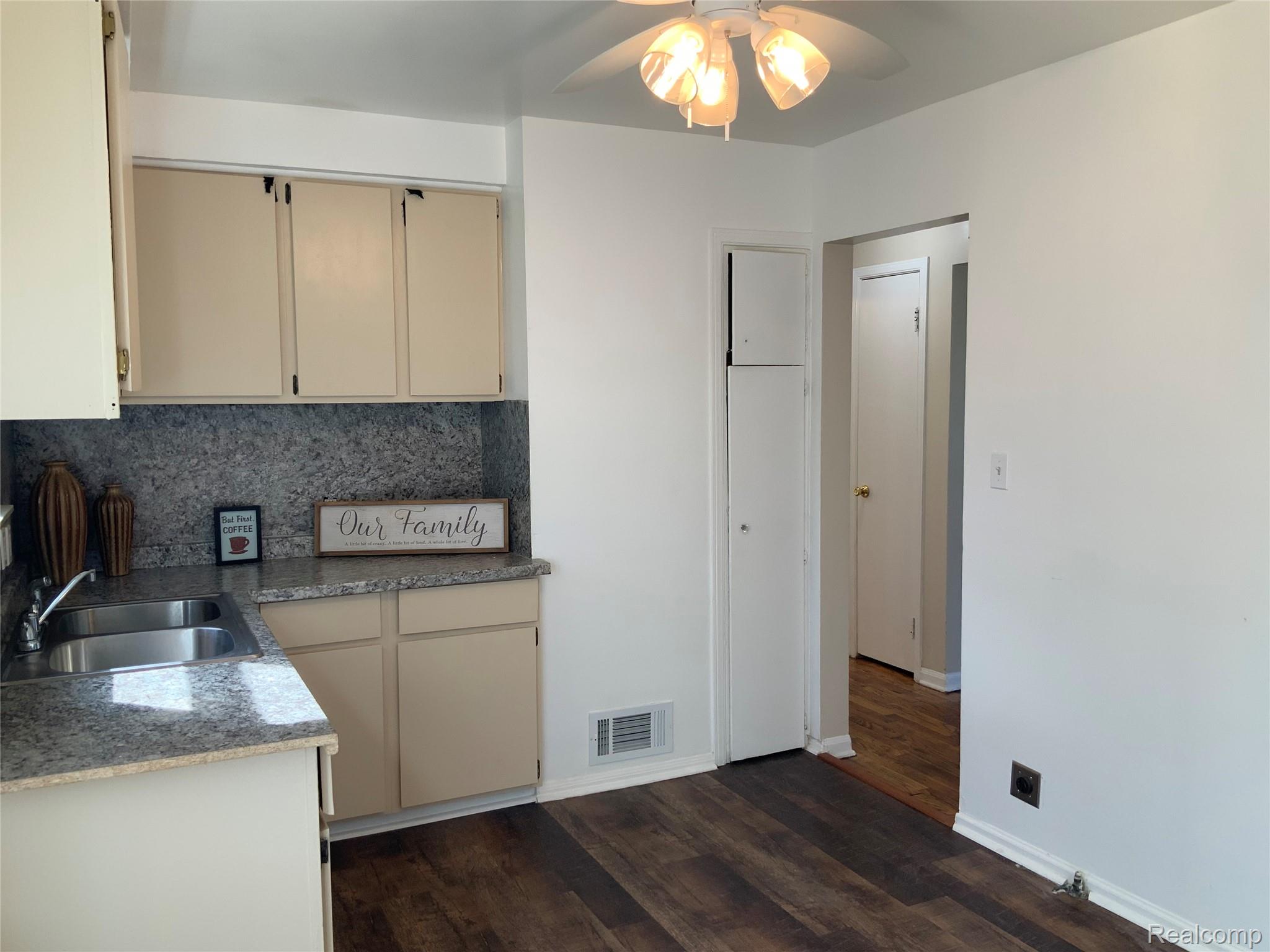 4034 Fleming Road Flint, MI 48504 - Photo 10 of 20 Dual-basin stainless steel sink, beige cabinetry, and wood-finish flooring