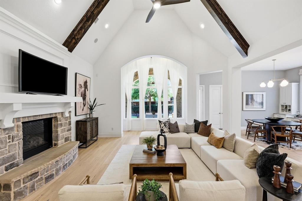 1933 Snapdragon Road Frisco, TX 75033 - Photo 14 of 40 Vaulted ceiling with exposed wood beams, stone fireplace, wood-finish flooring, and arched windows