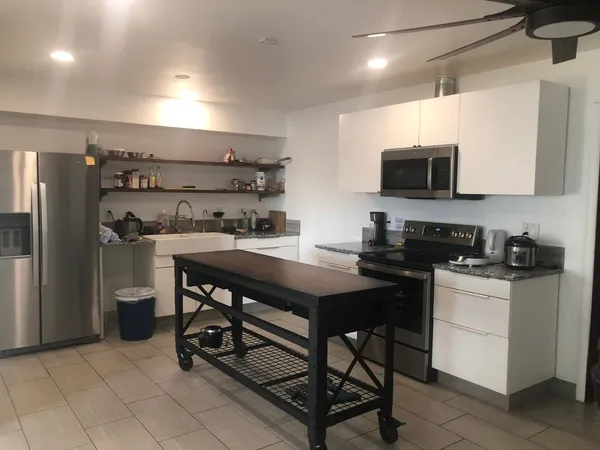a kitchen with stainless steel appliances a stove a sink a microwave a refrigerator and cabinets