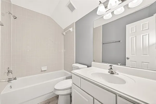 a bathroom with a sink a toilet a mirror a bathtub and shower