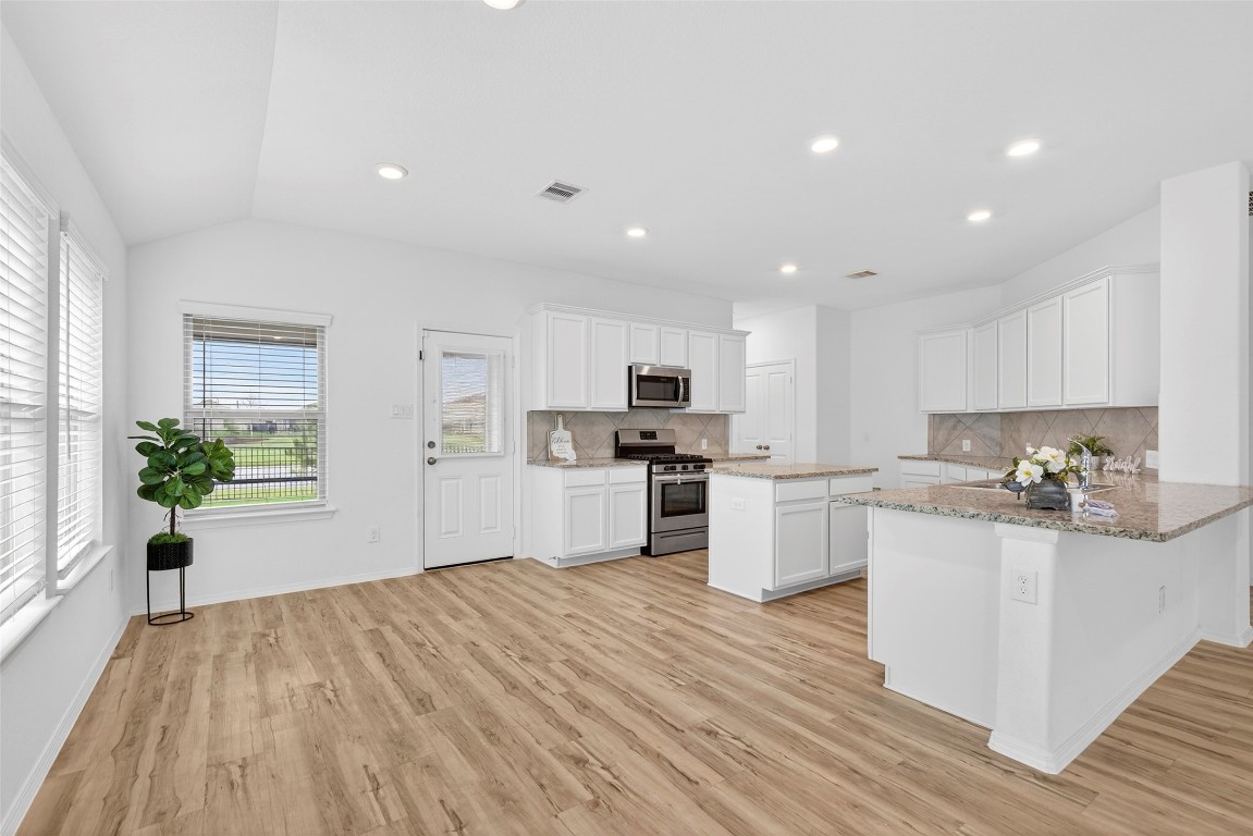 5402 Still Creek Ranch Drive Richmond, TX 77469 - Photo 13 of 32 a kitchen with white cabinets and wooden floor