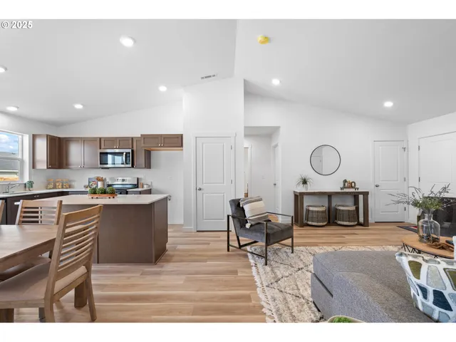 a living room with stainless steel appliances kitchen island granite countertop furniture and a wooden floor