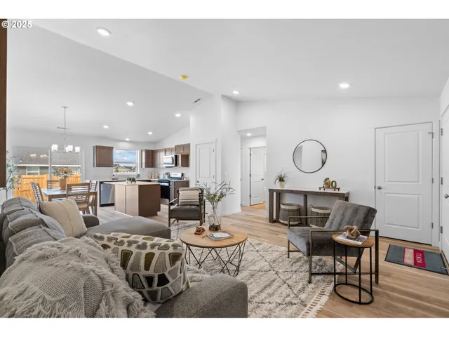 a living room with furniture kitchen view and a large window