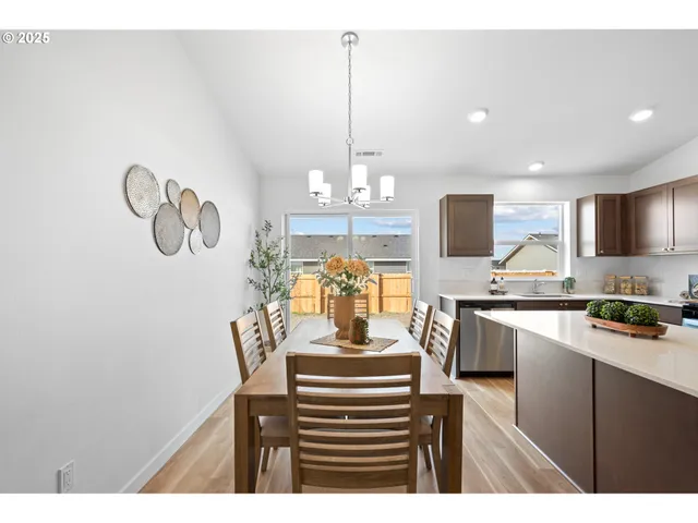 a kitchen with a refrigerator a stove a sink dishwasher a dining table and chairs with wooden floor