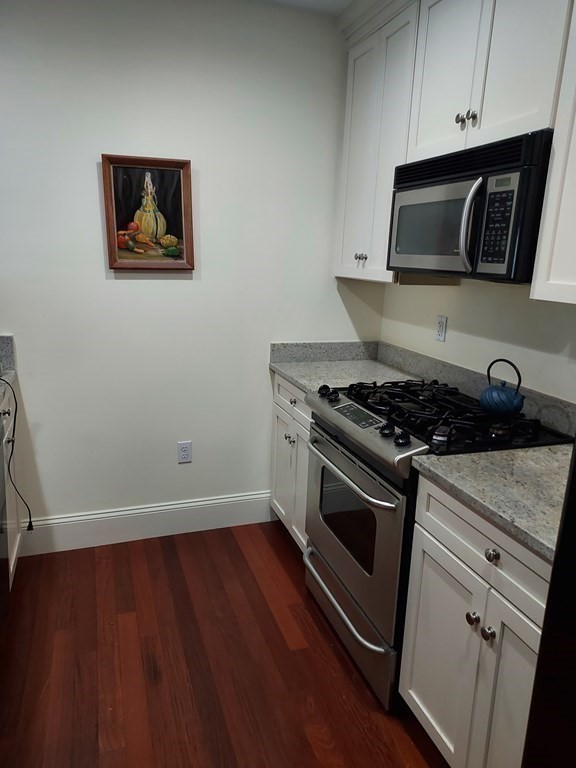 116 Rantoul Street, Unit 408 Beverly, MA 01915 - Photo 9 of 27 a kitchen with granite countertop stainless steel appliances a stove and a microwave